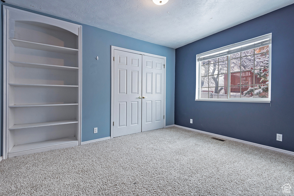 Unfurnished bedroom featuring visible vents, baseboards, carpet floors, a closet, and a textured ceiling