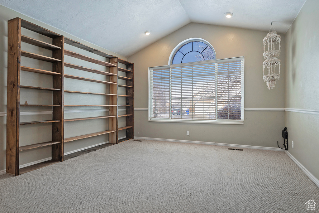 Carpeted empty room with baseboards, plenty of natural light, and vaulted ceiling