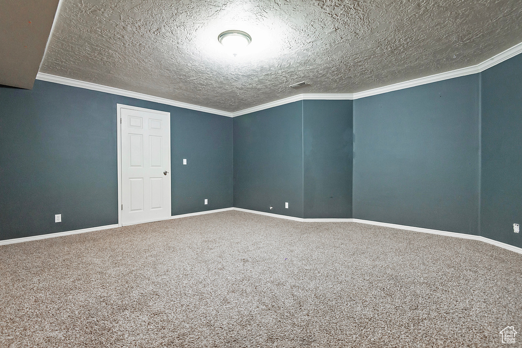 Unfurnished room featuring carpet flooring, a textured ceiling, baseboards, and ornamental molding