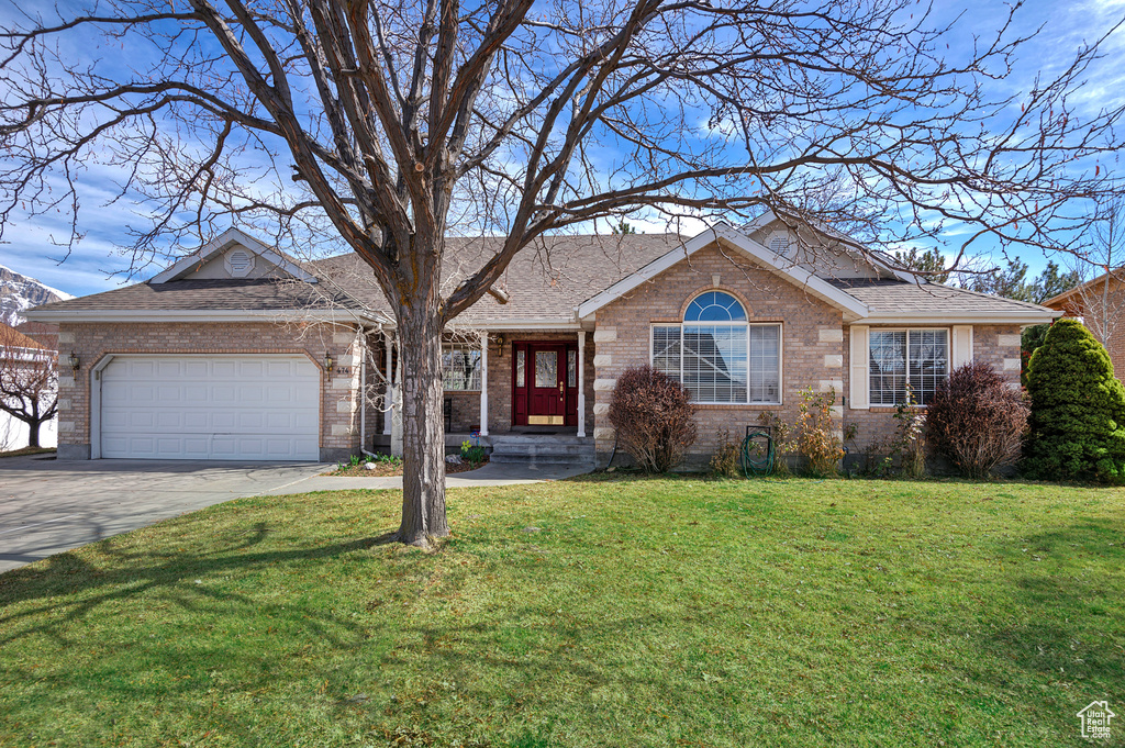 Ranch-style house with a garage, driveway, brick siding, and a front lawn