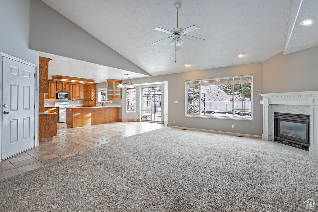 Unfurnished living room with a glass covered fireplace, plenty of natural light, light tile patterned flooring, and light carpet