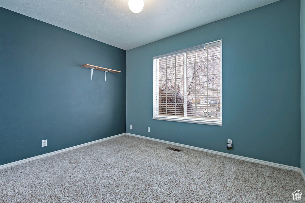 Empty room with visible vents, baseboards, carpet, and a textured ceiling