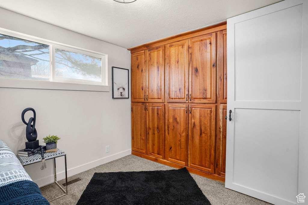 Bedroom featuring visible vents, baseboards, a textured ceiling, and light carpet