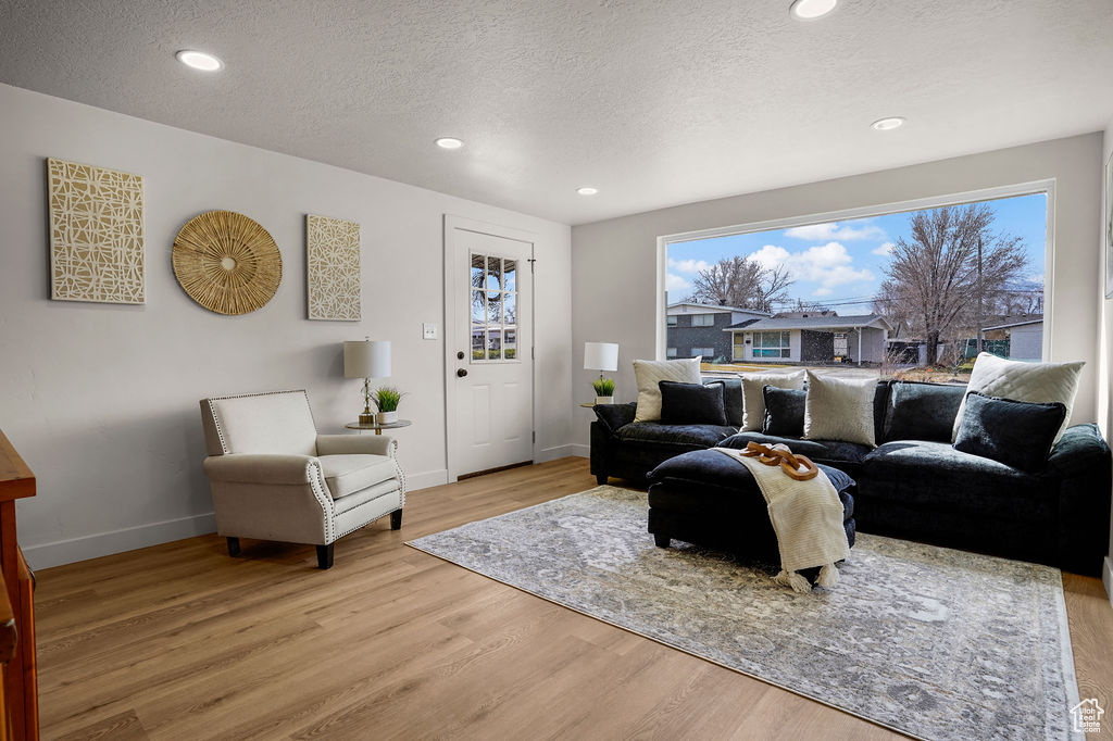 Living area with recessed lighting, baseboards, a textured ceiling, and light wood-style flooring