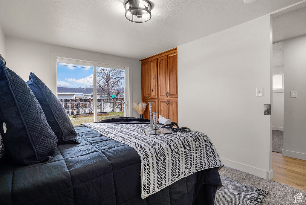 Bedroom featuring access to exterior, baseboards, and a textured ceiling