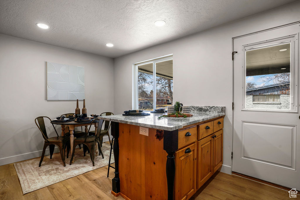 Kitchen with a textured ceiling, brown cabinetry, and light wood finished floors