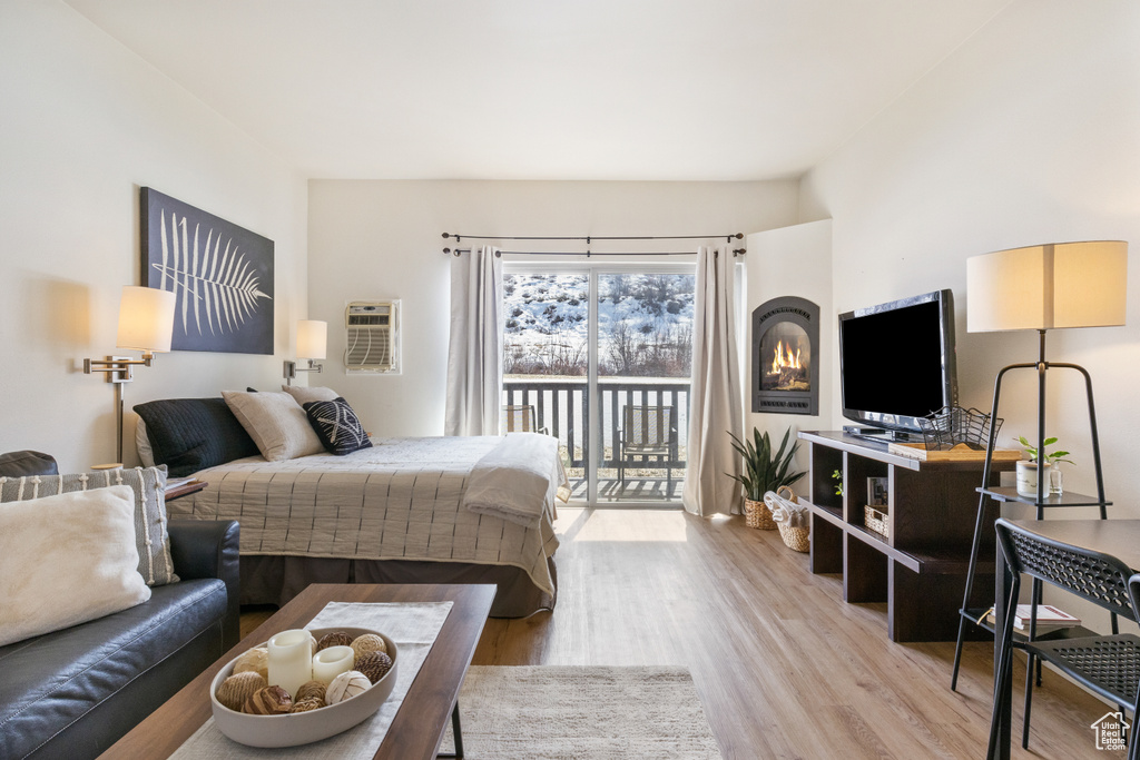 Bedroom featuring access to exterior, light wood-style flooring, and a wall unit AC