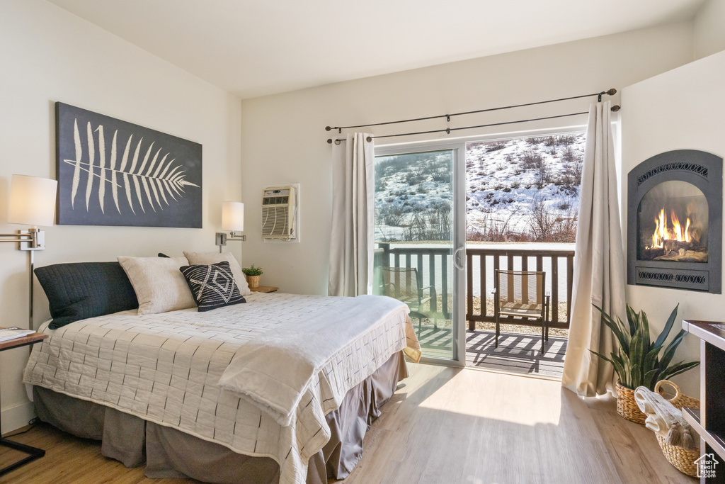 Bedroom featuring access to exterior, a wall mounted air conditioner, and wood finished floors