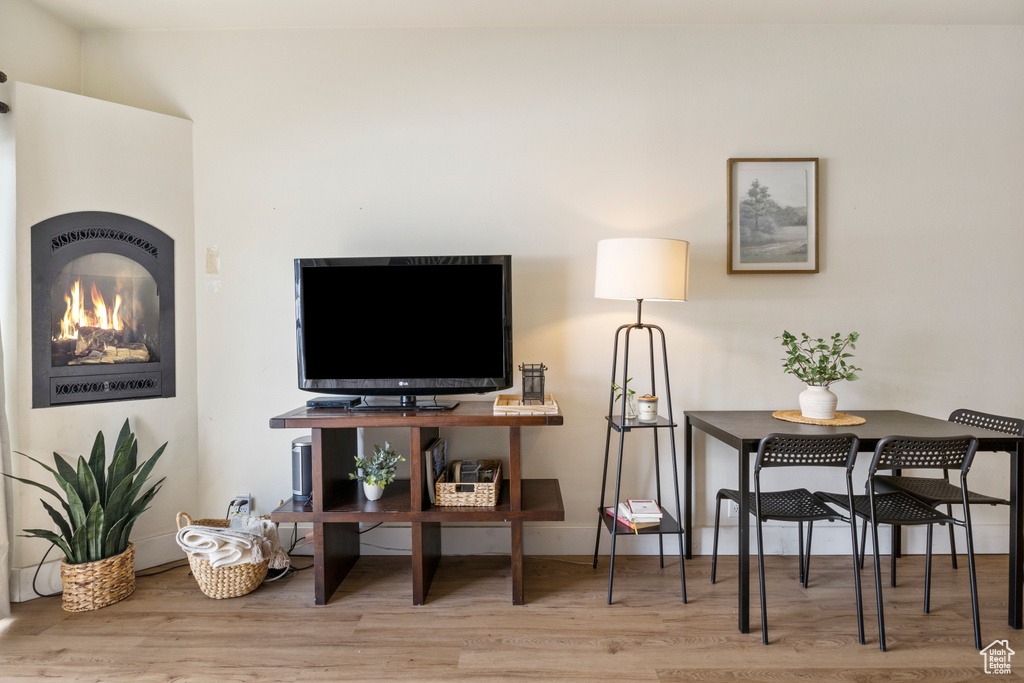 Living room with wood finished floors, baseboards, and a lit fireplace