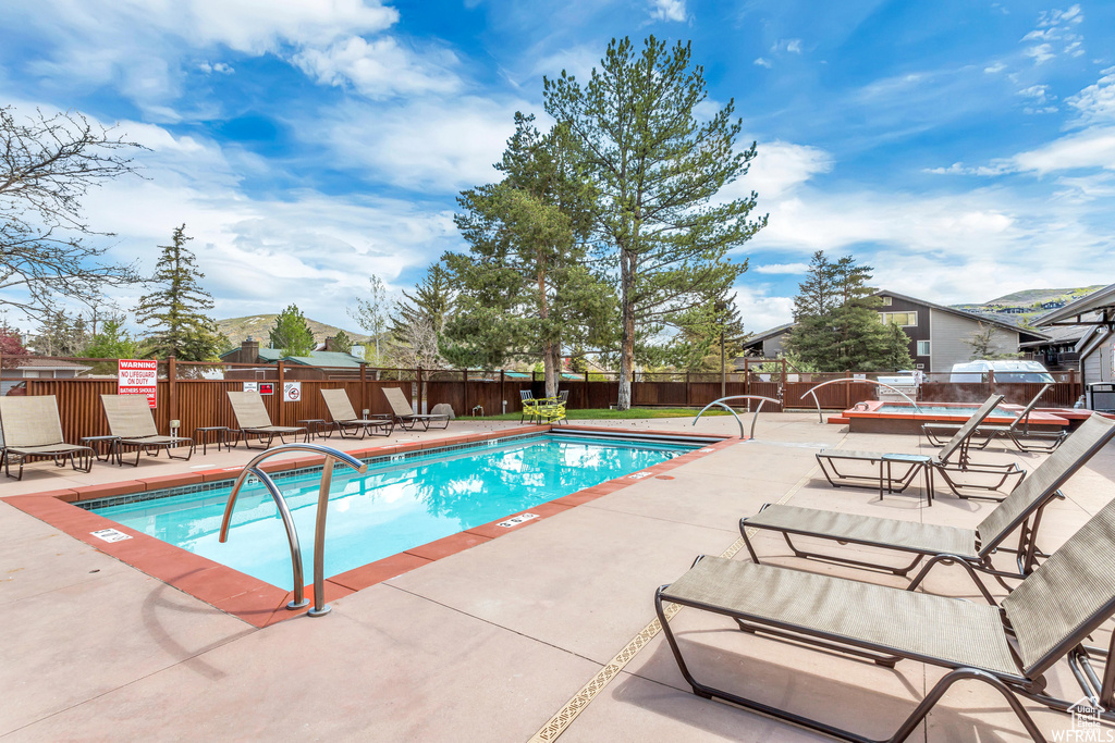 Community pool with a patio, a jacuzzi, and a fenced backyard