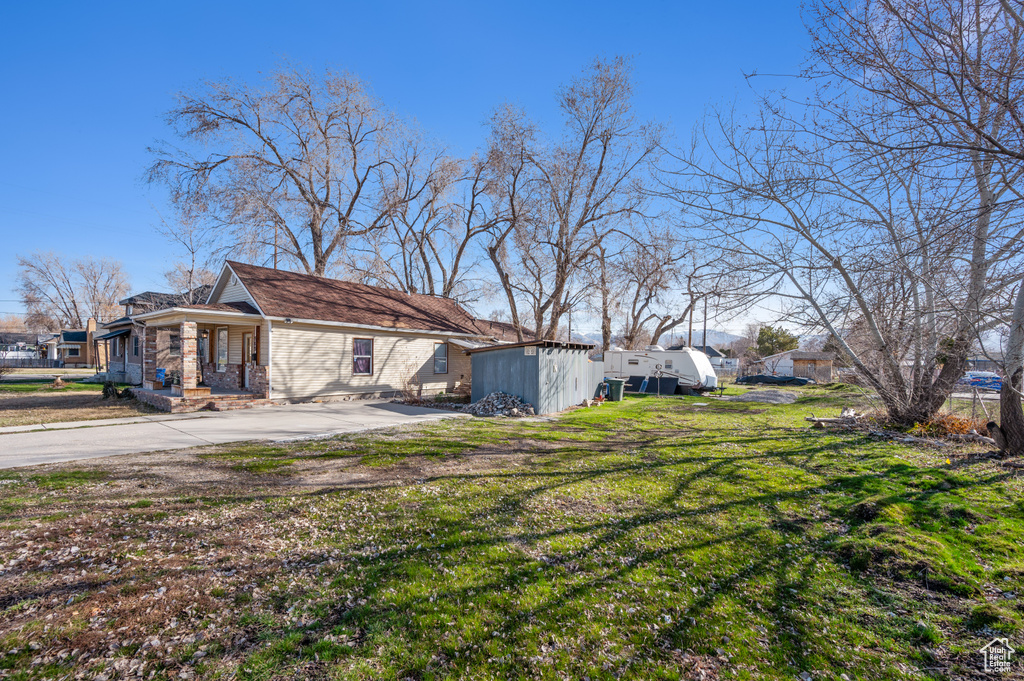 View of side of home featuring a yard, an outbuilding, and driveway