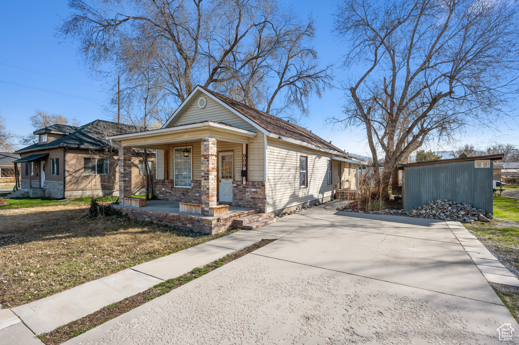 View of front of home with brick siding, covered porch, and driveway