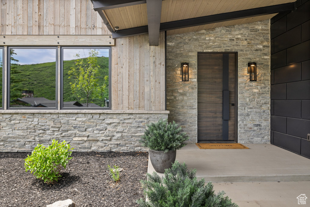 Doorway to property featuring stone siding and covered porch