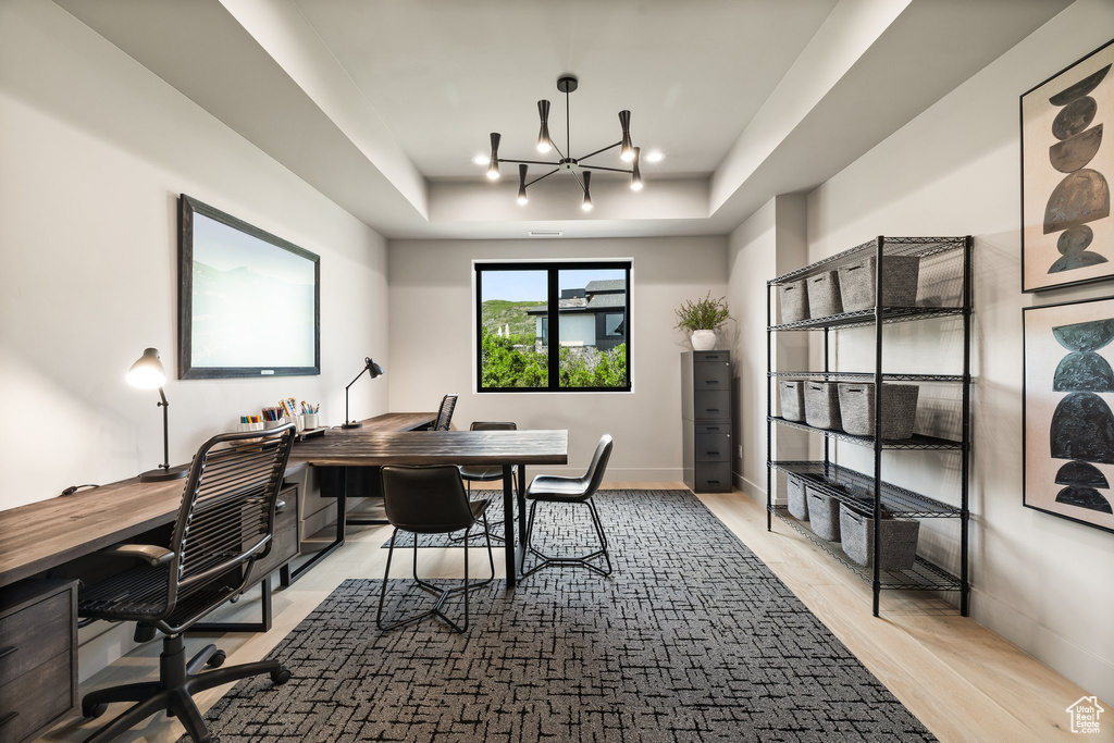 Office space featuring a raised ceiling, wood finished floors, a chandelier, and recessed lighting