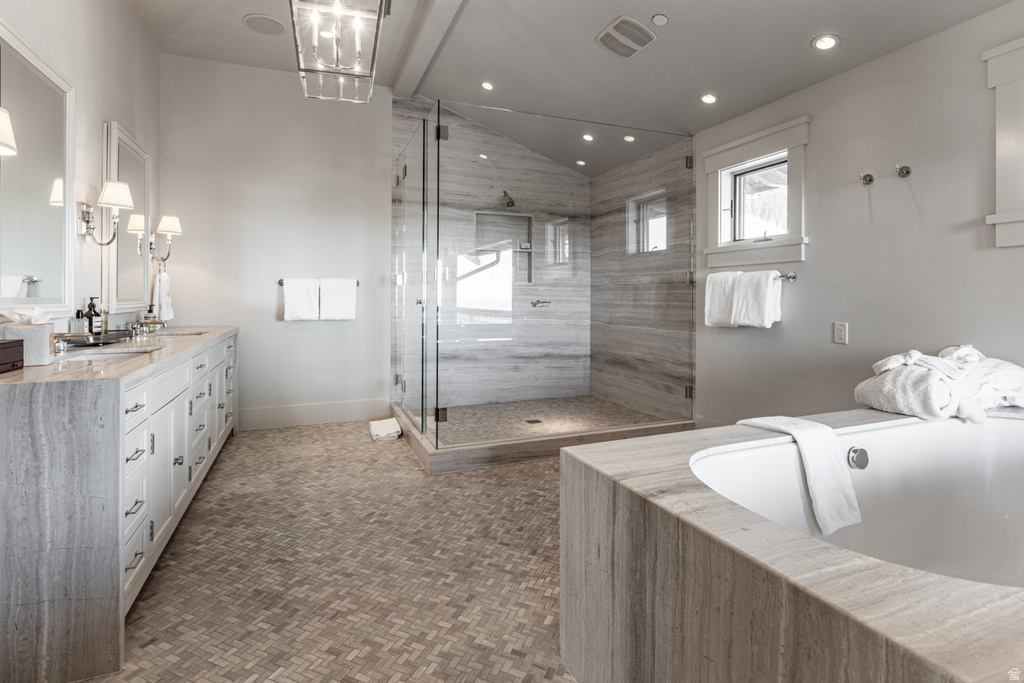 Full bathroom featuring double vanity, a bath, vaulted ceiling, a marble finish shower, and recessed lighting