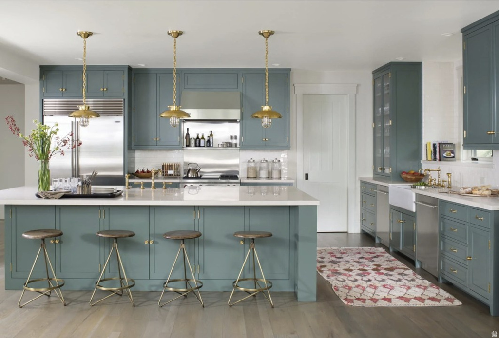 Kitchen featuring stainless steel built in fridge, a kitchen breakfast bar, dark wood-style flooring, decorative backsplash, and glass insert cabinets
