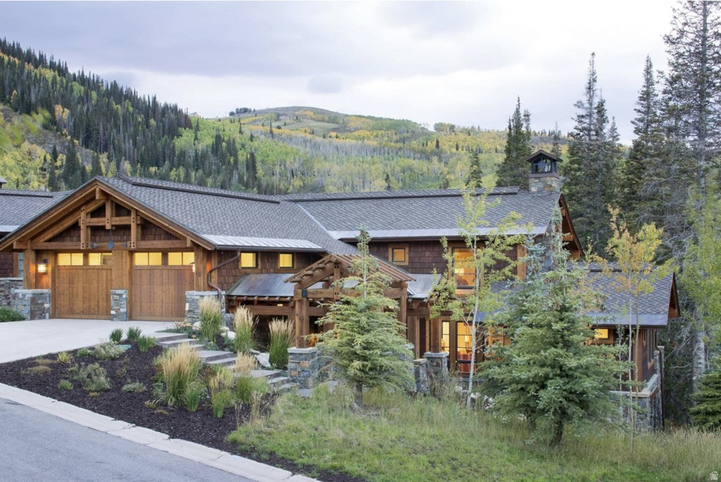 View of front of property with a chimney, a garage, driveway, a mountain view, and a standing seam roof