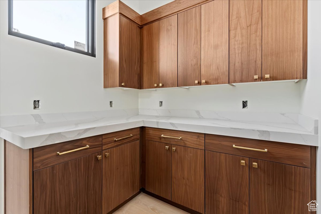 Kitchen with brown cabinetry and light stone counters