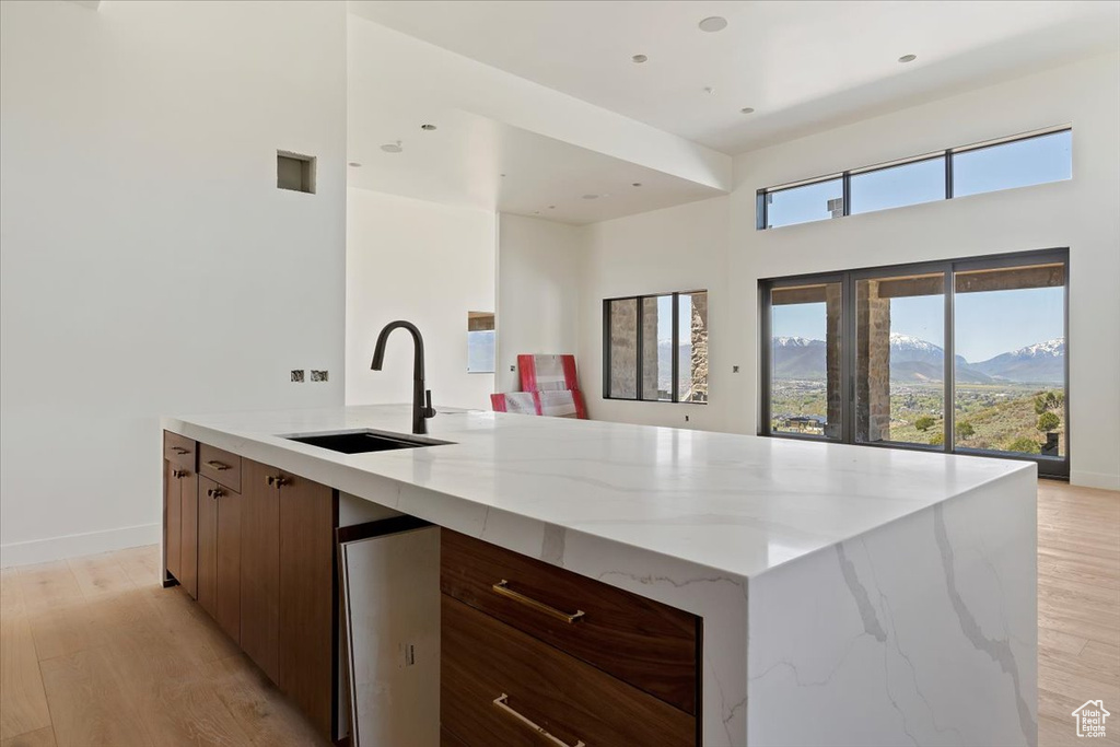Kitchen featuring a sink, modern cabinets, light stone countertops, light wood-style floors, and a high ceiling