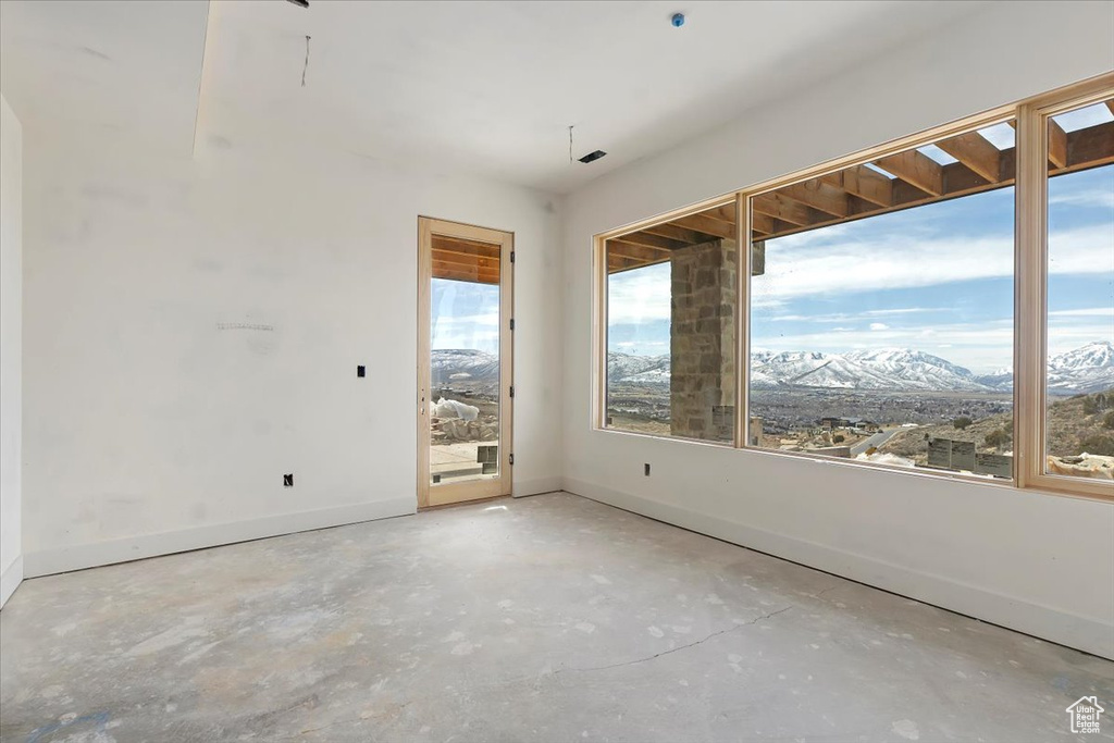Empty room featuring unfinished concrete floors, baseboards, and a mountain view