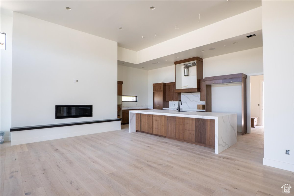 Kitchen featuring a sink, light wood-type flooring, light countertops, modern cabinets, and a large island