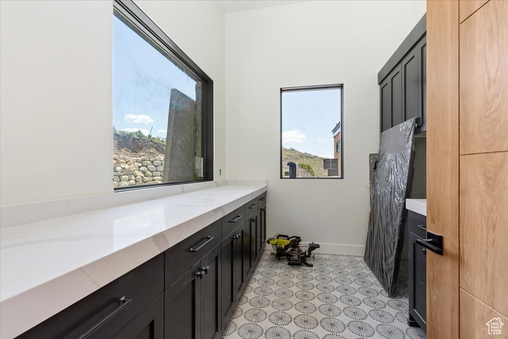 Bathroom with plenty of natural light, vanity, tile patterned floors, and baseboards