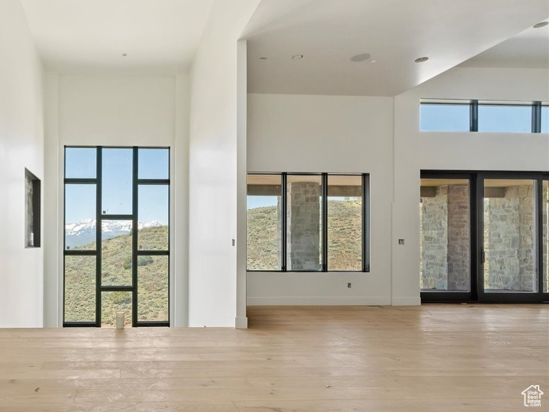 Unfurnished living room with a high ceiling, hardwood / wood-style flooring, and baseboards