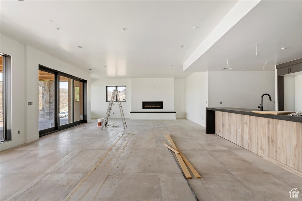 Unfurnished living room with a lit fireplace, a sink, and baseboards