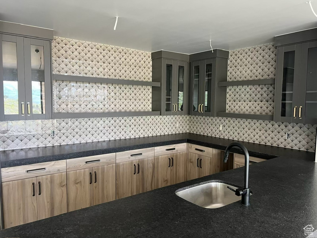 Kitchen with open shelves, a sink, tasteful backsplash, and light brown cabinets