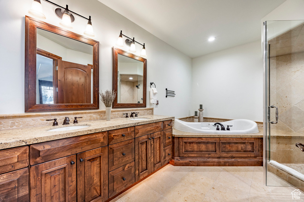 Bathroom featuring a sink, double vanity, a shower stall, and a bath