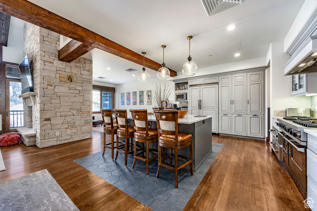 Kitchen featuring visible vents, built in appliances, a breakfast bar, dark wood-style floors, and light countertops