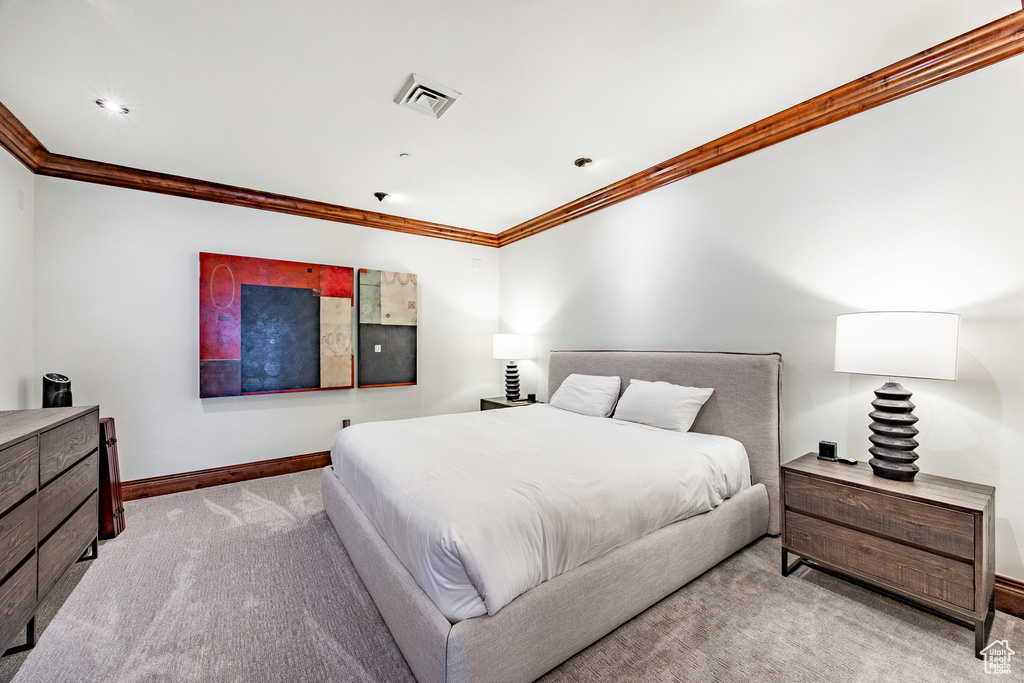Carpeted bedroom featuring crown molding, baseboards, and visible vents