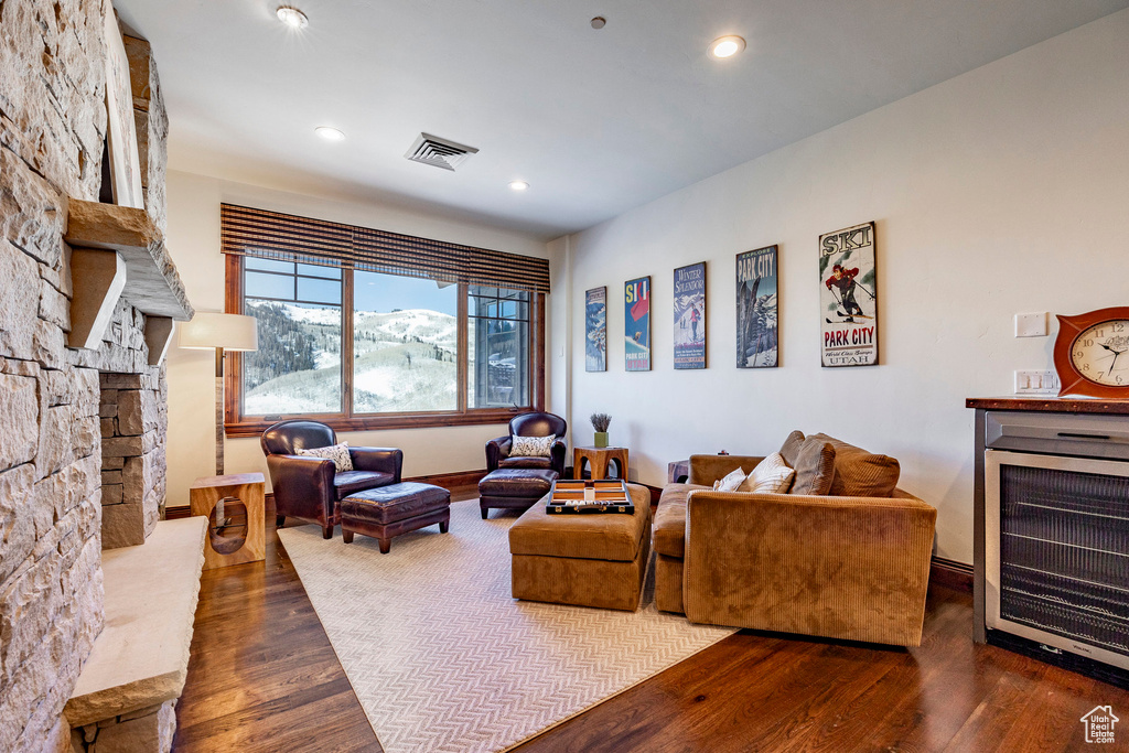 Living room featuring visible vents, wood finished floors, a stone fireplace, baseboards, and recessed lighting