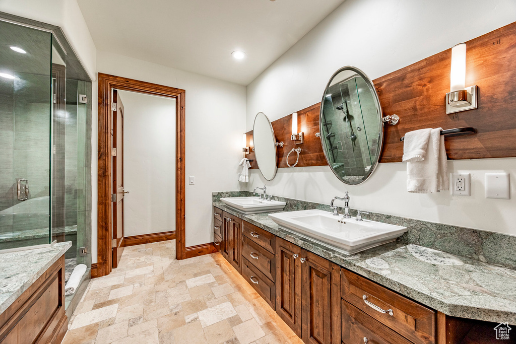 Bathroom with a sink, double vanity, a shower stall, and stone tile flooring