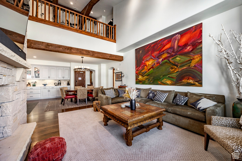 Living area featuring dark wood-style flooring, beamed ceiling, a high ceiling, recessed lighting, and arched walkways