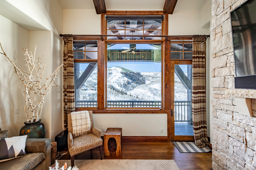 Sitting room with a ceiling fan, wood finished floors, a wealth of natural light, and beamed ceiling