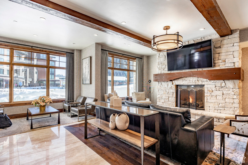 Living area featuring recessed lighting, a stone fireplace, plenty of natural light, and beam ceiling