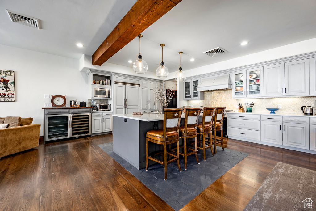 Kitchen featuring built in appliances, premium range hood, tasteful backsplash, visible vents, and dark wood-type flooring