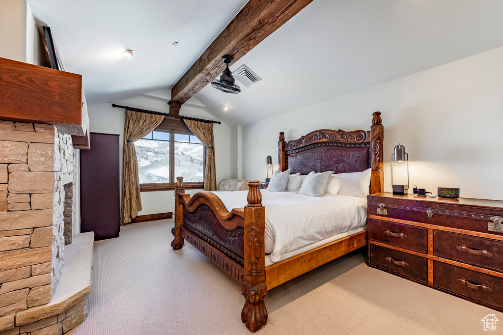 Bedroom with light colored carpet, visible vents, and vaulted ceiling with beams