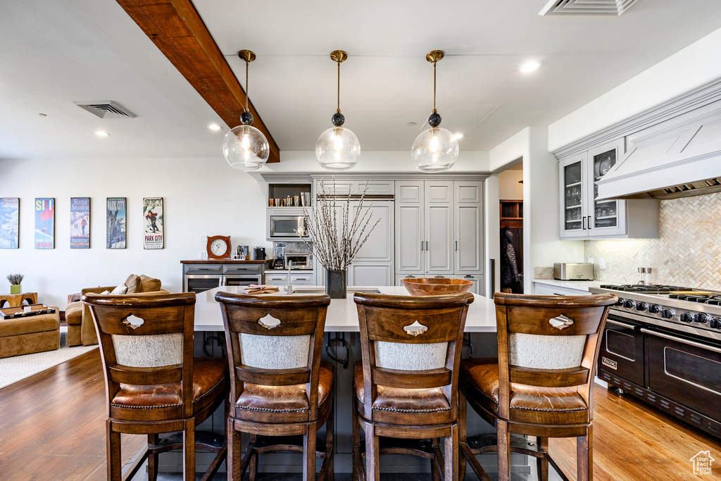 Kitchen with visible vents, a kitchen breakfast bar, stainless steel microwave, range with two ovens, and backsplash