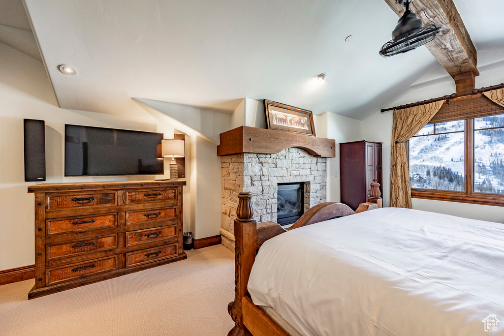 Bedroom with carpet floors, baseboards, a stone fireplace, and lofted ceiling