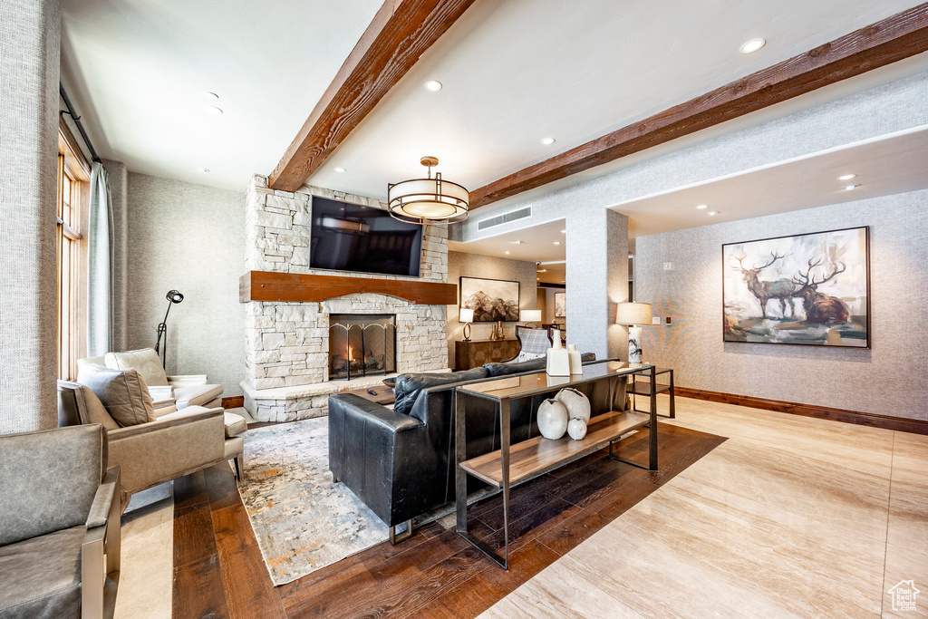 Living area featuring visible vents, wood finished floors, a fireplace, and beamed ceiling