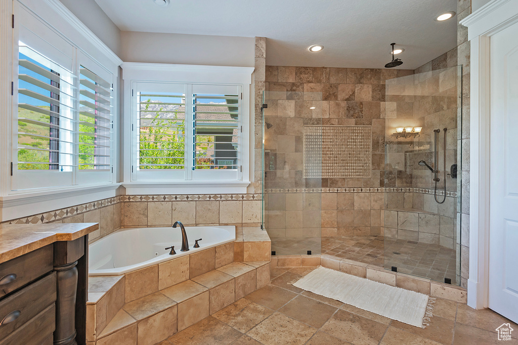 Full bath featuring stone tile flooring, a garden tub, a stall shower, and recessed lighting
