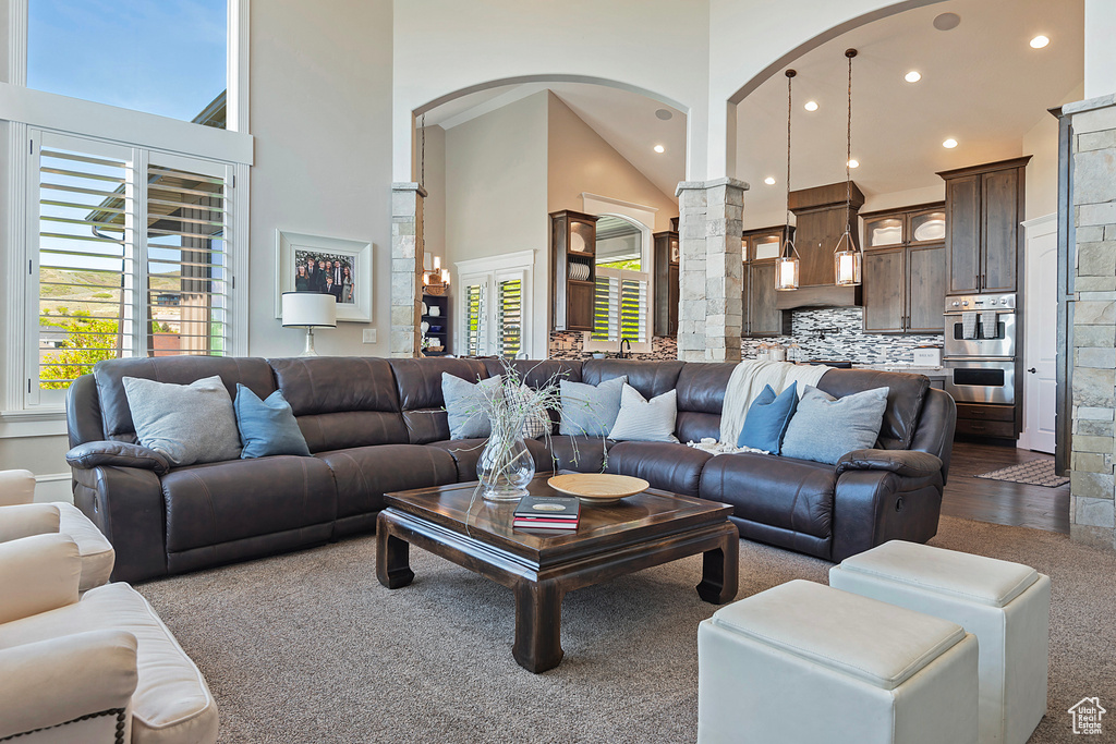 Living room with ornate columns, arched walkways, a towering ceiling, recessed lighting, and dark carpet