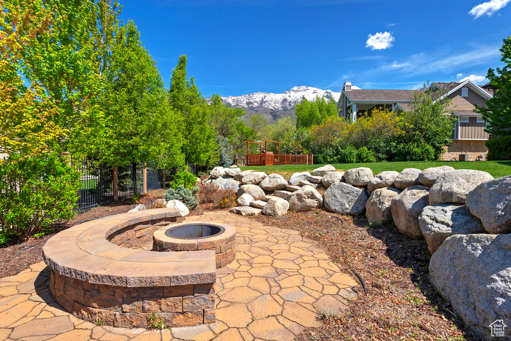 View of patio with a fire pit, fence, and a mountain view