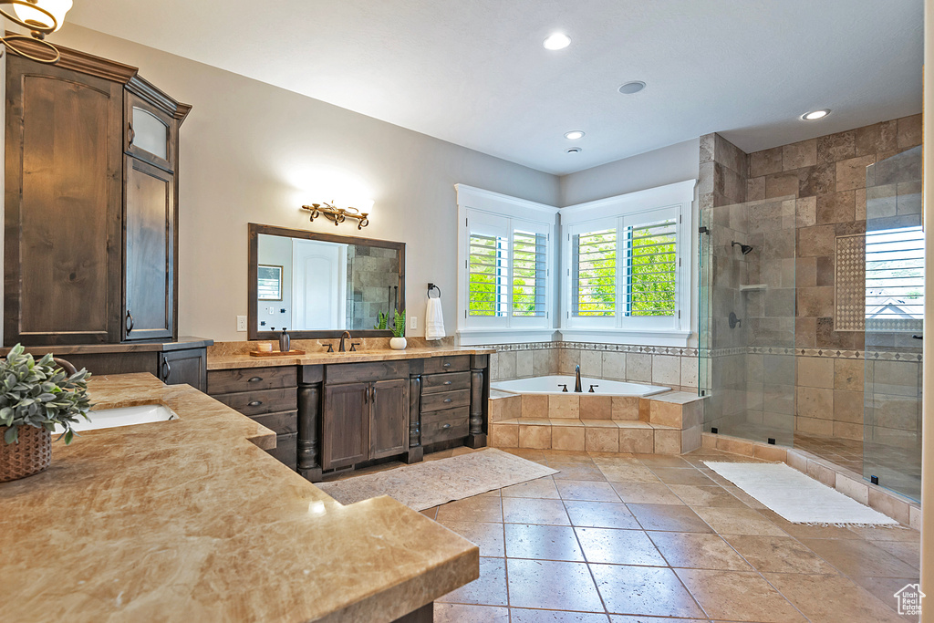 Bathroom featuring a shower stall, a garden tub, two vanities, recessed lighting, and stone tile floors