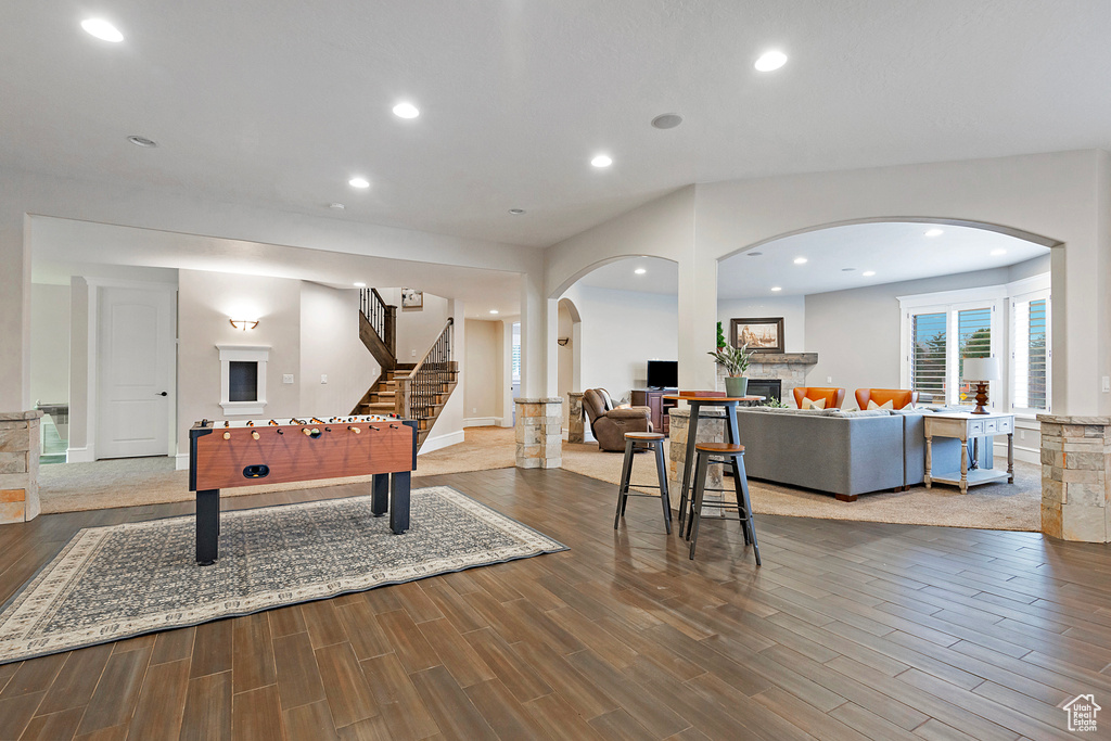 Playroom with wood finished floors, a fireplace, arched walkways, recessed lighting, and baseboards