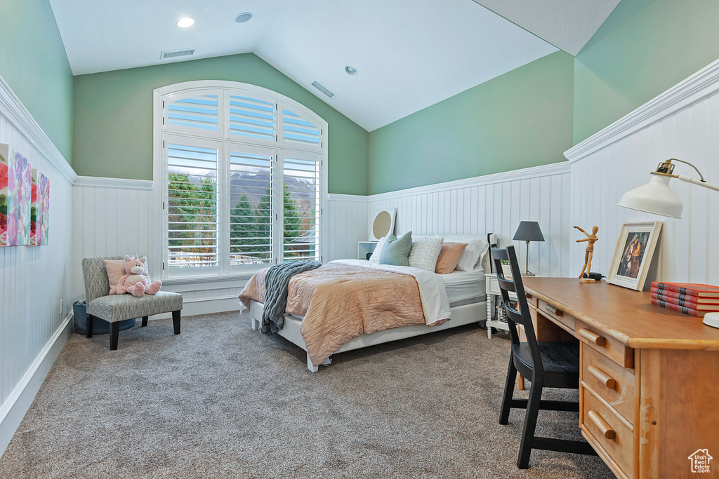 Carpeted bedroom with visible vents, wainscoting, and lofted ceiling