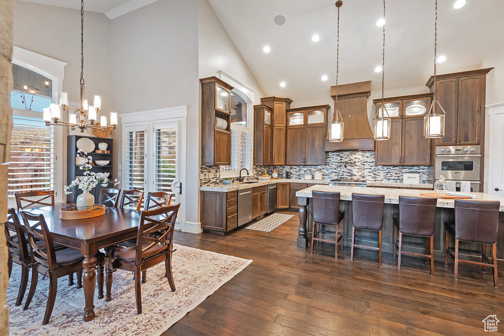 Dining space featuring high vaulted ceiling, a chandelier, dark wood-style floors, and recessed lighting