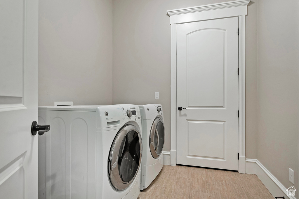 Laundry room featuring independent washer and dryer, baseboards, and light wood-style flooring